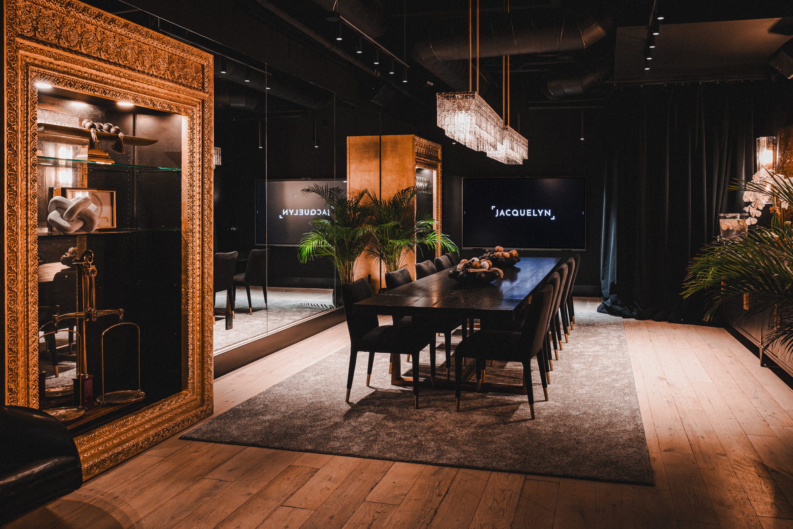 The Boardroom: long dark conference table, chandelier, Jacquelyn screen and a gilded mirror display case